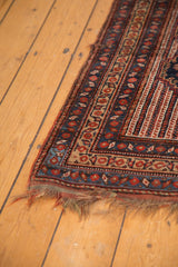 Corner of an antique Persian Kamseh rug, showcasing intricate geometric borders, low pile, and tattered fringe.