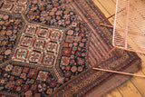 Antique Kamseh rug corner, displaying dense geometric motifs in navy, red, and original aged edge.
