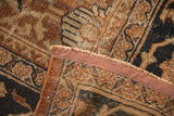 Antique Mahal rug folded corner revealing short fringe, reddish-brown binding, and aged chocolate bronze patterns.