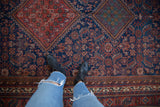 Detail of a vintage Afshar carpet showing tribal medallions in cherry red, green, and indigo.