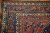 Intricate tribal borders of a vintage Persian Afshar rug in cherry red, indigo, and ivory.