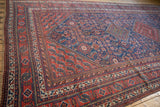 Angled view of a vintage Afshar runner highlighting its tribal motifs and complex cherry red and indigo borders.