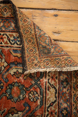 Mahal rug folded corner reveals worn Herati pattern, exposed foundation, and fringe.