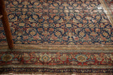 Intricate herati and mahi pattern on distressed dark indigo and red antique Malayer rug.