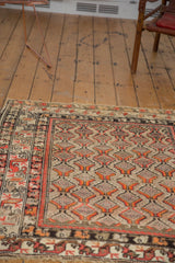 Antique Hamadan rug displays geometric field of red and orange plant motifs with stylized border.