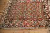 Antique Hamadan rug corner, displaying intricate germinating plant field and stylized red, ivory borders.