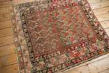 Antique Hamadan rug corner, intricate red and oxidized silver shrub border, geometric plant field.
