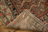 Antique Hamadan rug corner lifted, showing hand-knotted foundation, fringe, and abrashed low pile.
