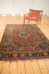 Antique Qashqai rug's hand-knotted fringe and border with madder red, navy, tangerine floral motifs.