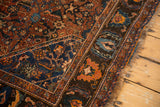 Antique Qashqai rug corner, intricate madder, navy, sky blue Herati patterns and tattered fringe.