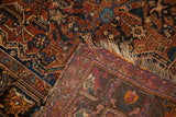Detail of antique Qashqai rug's hand-knotted foundation, worn fringe, and intricate pattern.