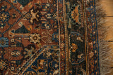 Vibrant madder red and navy blue Herati patterns on antique Qashqai rug with secured fringe.