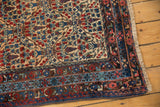 Vintage Kurdish Bijar rug corner with cypress trellis pattern, layered borders in madder red and blue, light fringe.