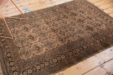 Distressed texture on vintage Afghan rug, pale camel gold and dark brown gul motifs.