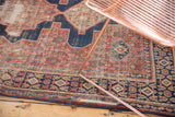 Distressed vintage Senneh rug section: intricate herati motif in cherry, indigo, and ivory tones.