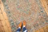 Time-softened pale camel and blue curvilinear motifs on a distressed vintage Heriz rug.