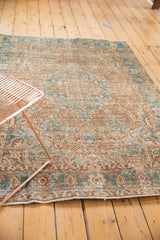 Distressed vintage Heriz rug surface with pale camel and powder blue curvilinear motifs.