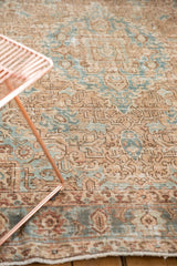 Distressed vintage Heriz rug's faded camel and powder blue patterns, showing even wear.