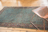 Distressed aqua blue Kerman rug field with scrolling tendrils and faded burgundy motifs.