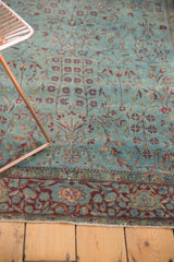 Distressed antique Kerman rug with intricate burgundy floral border and delicate vinery, showing even wear.