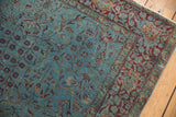 Distressed aqua blue and burgundy floral patterns on the antique Kerman rug border.