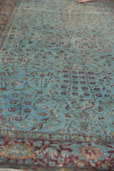 Intricate faded aqua blue vinery and exposed knot heads on this antique distressed Kerman rug.