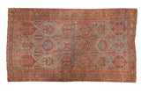 Vintage Baktiari carpet with distressed geometric design in muted blue and red tones.