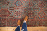 Distressed vintage Persian Baktiari carpet featuring an allover geometric pattern in dusty blue and wine red.