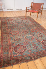 Distressed Baktiari carpet with faded dusty blue and wine red multi-paneled motifs.