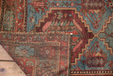 Folded distressed Baktiari carpet corner reveals worn pile, geometric motifs, and its woven backing.