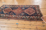 Antique Caucasian Kazak runner's corner, highlighting geometric palmettes, worn madder root red, and navy tones.