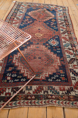 Antique Kazak rug's lower corner, displaying geometric border and madder root red field motifs.