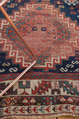 Antique Caucasian Kazak runner: cherry red, navy, ivory geometric motifs, wear, and fringe.