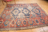 Fragmented antique Caucasian rug detail: brick red field, navy stylized motifs, visible wear.