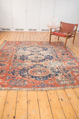 Secured lower edge of the antique Caucasian rug, showcasing time-softened brick red and navy patterns.