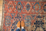 Antique Caucasian Soumac fragment's dense geometric field in brick red, navy blue, and ivory with visible wear.