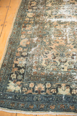 Distressed Hamadan carpet featuring ornate seafoam blue border and visible foundation.