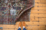 Worn violet, sky blue, and ivory curvilinear motifs on a distressed vintage Baktiari carpet.