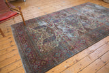 Distressed Baktiari carpet showing curvilinear motifs in violet, blue, and ivory tones.