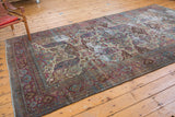 Distressed Baktiari rug with curvilinear motifs in violet and blue, showing visible foundation.