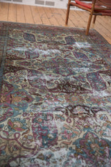 Distressed Baktiari carpet showing curvilinear Safavid-inspired motifs in violet, blue, and ivory.