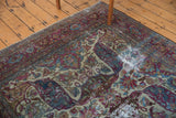 Distressed Baktiari carpet detail: curvilinear Safavid-inspired motifs with worn pile and violet tones.