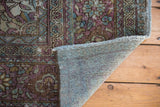 Distressed vintage Baktiari rug corner revealing hand-knotted foundation and worn fringe.
