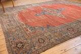 Corner detail of an antique Persian Mahal carpet with madder red field and richly patterned borders.
