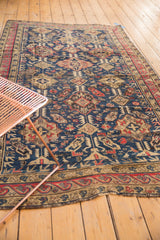 Antique Soumac carpet: tribal geometric patterns in navy, cherry red, and ivory, fringe detail.