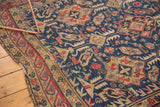 Hand woven antique Soumac carpet corner, featuring navy field, geometric cherry red border, and fringe.