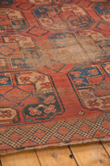 Detail of vintage hand-knotted carpet corner: madder red field, sky blue guls, geometric border, visible wear.
