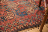 Vintage Afghan carpet detail: geometric blue, brown border, madder red field with guls, softened pile.