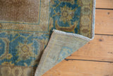 Distressed vintage Agra rug corner with worn brown-bronze, sky blue pile and woven foundation.