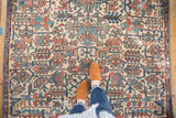 Distressed Heriz carpet with ivory, sky blue, and faded red allover geometric patterns and visible wear.